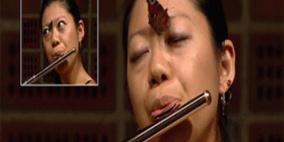 فراشة تقف على أنف عازفة فلوت أثناء مسابقة موسيقى كبرى