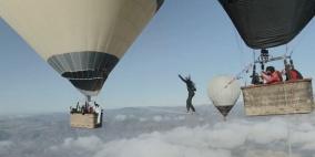 بالفيديو .. مغامرون يسيرون على حبل رفيع بين منطادين على ارتفاع شاهق