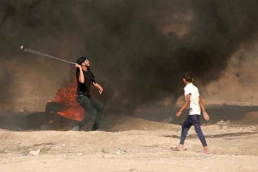 شاب يلقي الحجارة على حدود غزة
