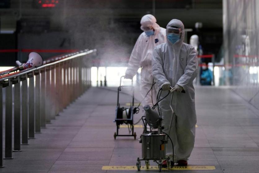 عمال في محطة قطارات بمدينة شنغهاي الصينية يرشون مطهرات لمواجهة انتشار مرض كورونا