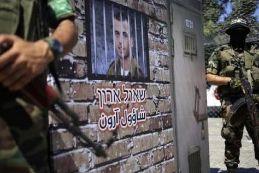 عناصر من القسام يقفون بجانب صورة الاسرائيليين الاسرى