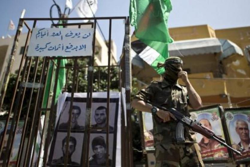 عنصر من القسام يف امام صورة للجنود الاسرى في غزة