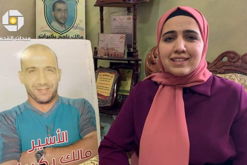بنت الاسير بكيرات بجانب صوره لوالدها