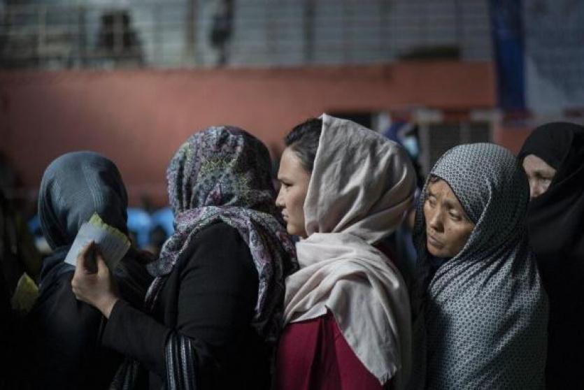 نساء أفغانيات ينتظرن دورهن باستلام معونات غذائية