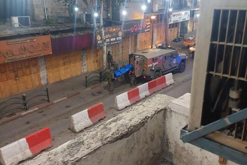 جنود الاحتلال يحتجزون جثماني الشهيدين، بمنطقة باب الزاوية في الخليل